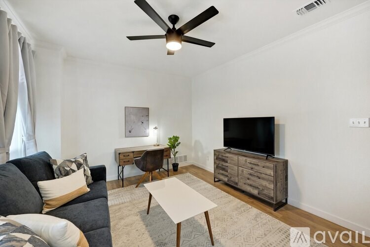 A living room with a grey couch, a white coffee table, and a wooden cabinet.