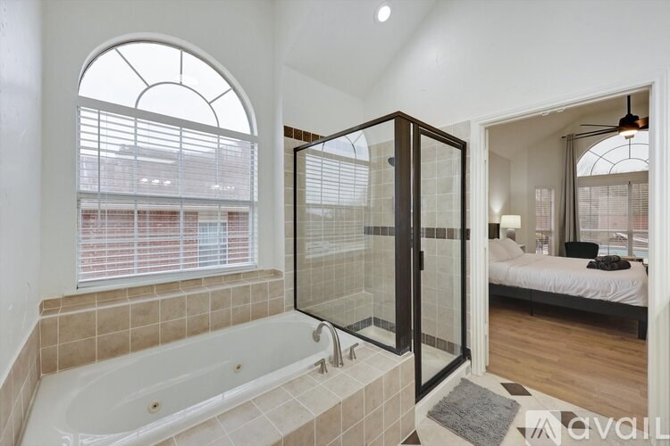 A bathroom with a tub and a bedroom in the same room.