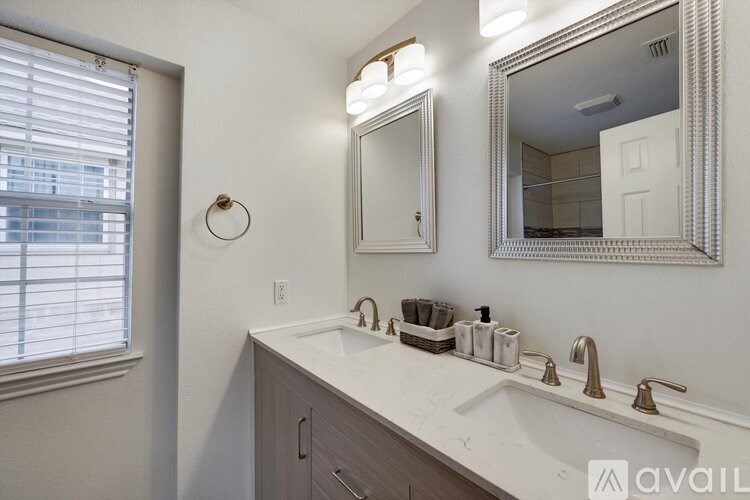 A bathroom with a sink, mirror, and a window with blinds.