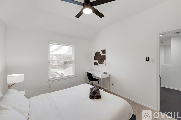A bedroom with a bed, desk, and window.