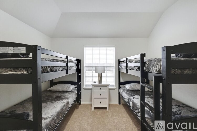 A room with bunk beds and a desk with a window.