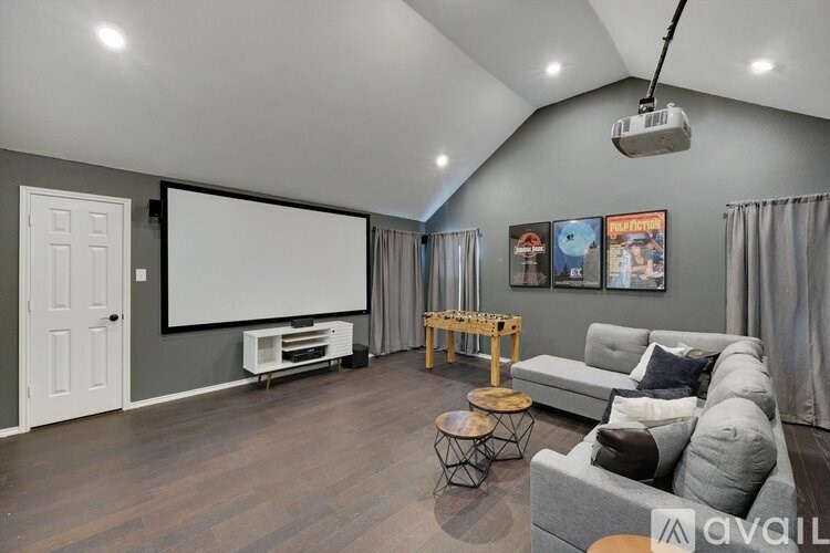 A living room with a grey couch, a wooden table, and a white door.