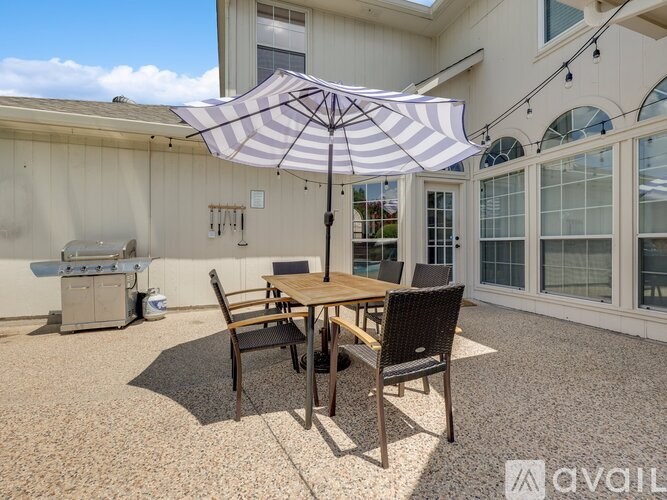 A patio with a table and chairs under an umbrella.