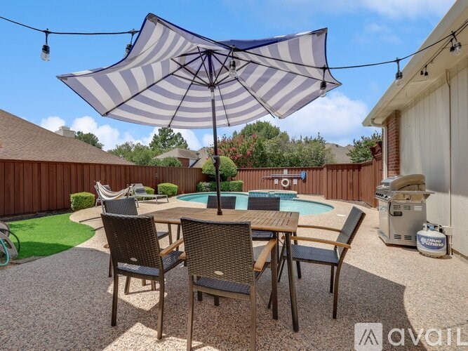 A patio with a table and chairs under an umbrella.