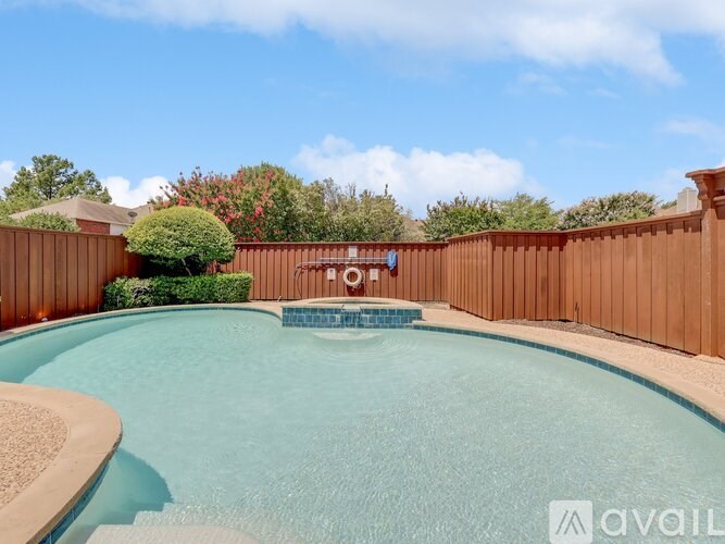 A pool surrounded by a wooden fence and a bush.