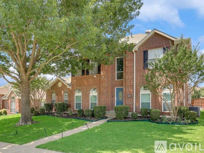 A red brick house with a green lawn in front.