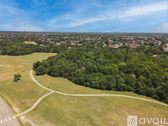 A bird's eye view of a green field with a road and a tree.
