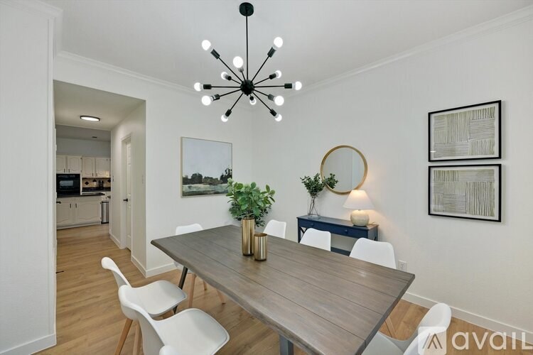 A modern dining room with a wooden table and white chairs.