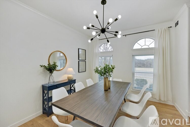 A dining room with a wooden table and white chairs.