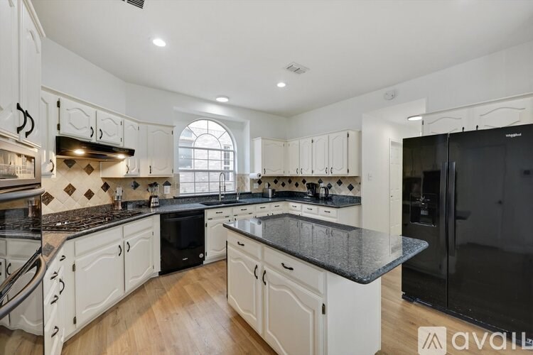 A kitchen with white cabinets and a black countertop.