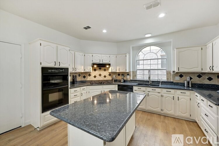 A kitchen with a granite countertop and white cabinets.