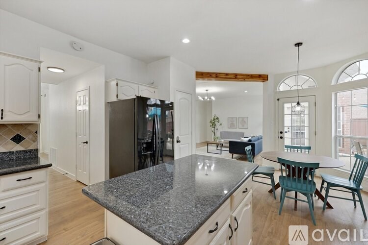 A kitchen with granite countertops and a dining area with a table and chairs.