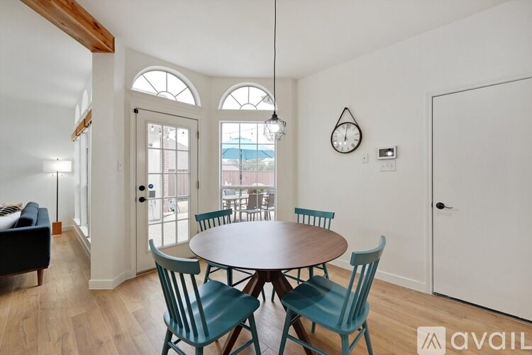 A dining room with a table set for four and chairs around it.