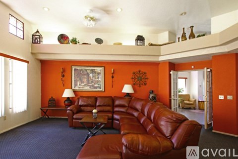 A living room with a red couch and a painting on the wall.