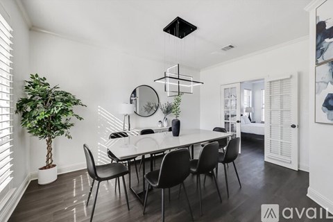 A dining room with a white table and black chairs.