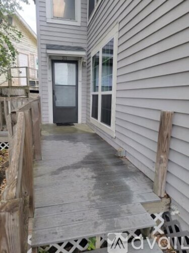 A grey house with a wooden deck and a glass door.