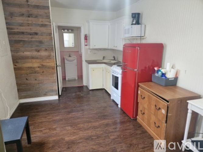 A kitchen with a red fridge and wooden floors.