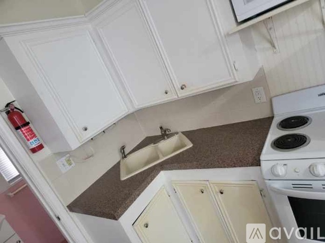 A kitchen with white cabinets and a white stove top oven.
