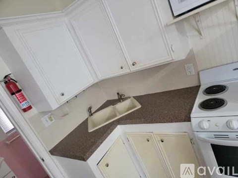 A kitchen with white cabinets and a white stove top oven.