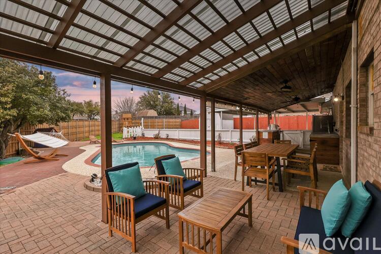 A patio with a table and chairs overlooking a pool.