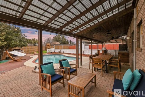 A patio with a table and chairs overlooking a pool.