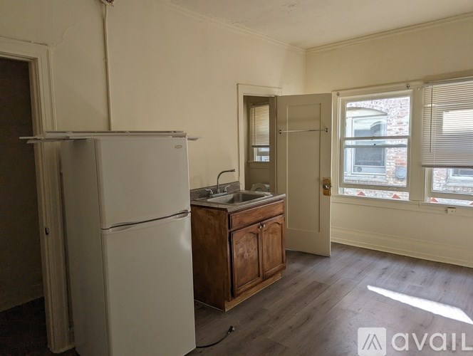 A kitchen with a white fridge, wooden cabinets, and a window with blinds.