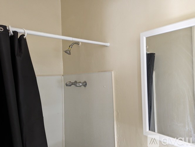 A white bathroom with a black shower curtain and a white door.