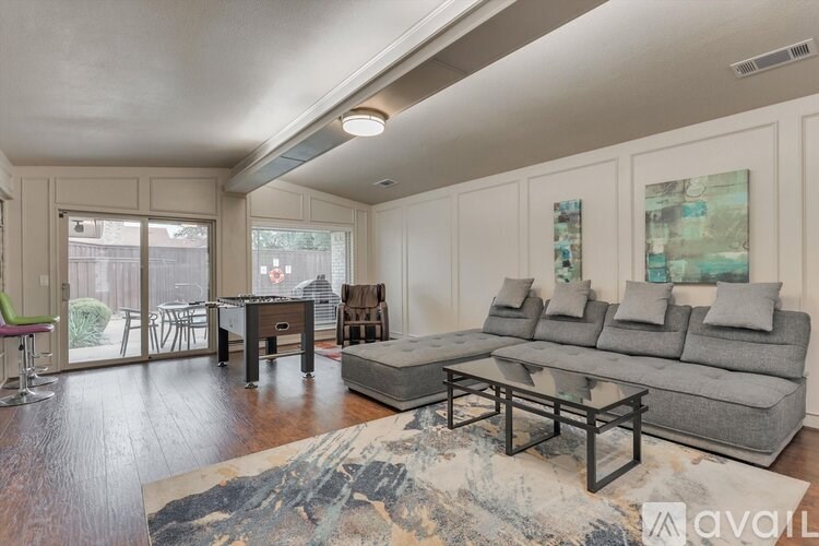 A living room with a grey couch and a rug on the floor.