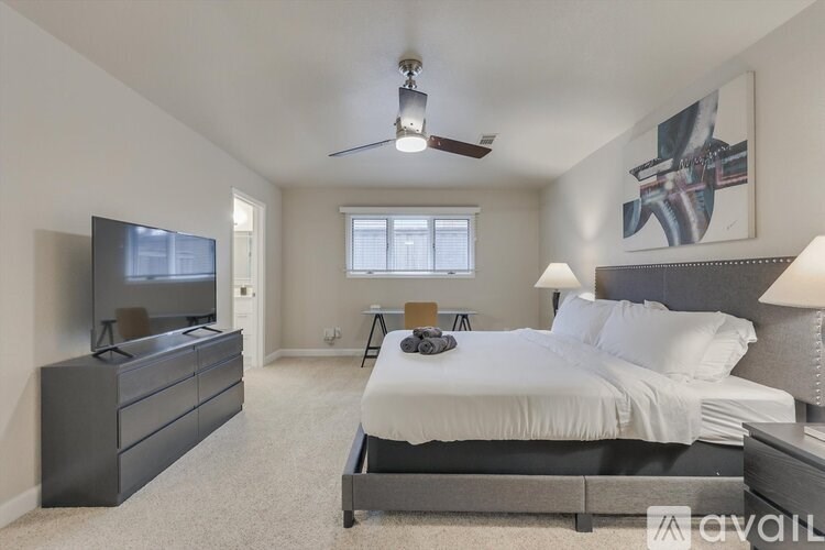 A bedroom with a large bed, a flat screen TV, and a ceiling fan.