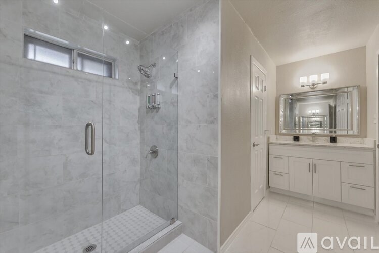 A bathroom with a walk-in shower and a vanity with a mirror.