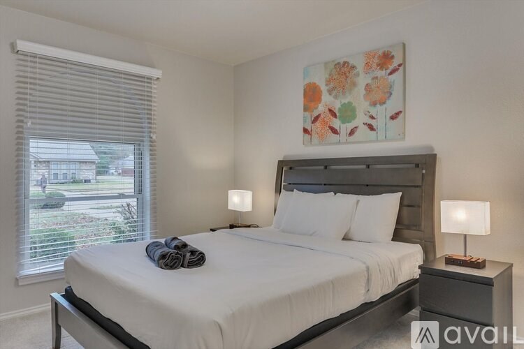 A bedroom with a large bed and a window with blinds.