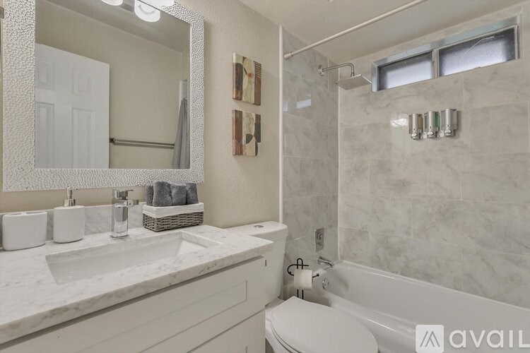 A bathroom with a white tub, sink, and mirror.