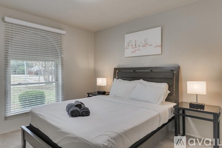 A bedroom with a large bed and a window with blinds.
