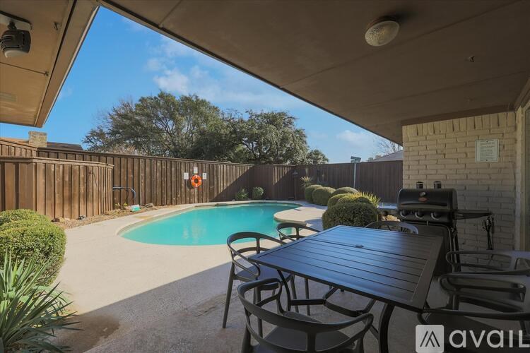 A pool area with a table and chairs under a roof.