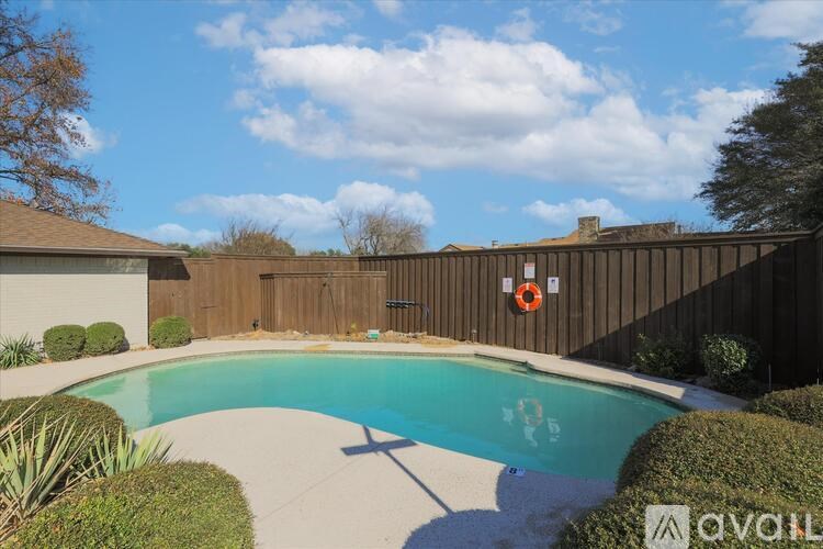A pool surrounded by a wooden fence and bushes.