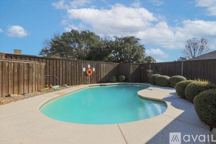 A swimming pool surrounded by a wooden fence and green bushes.