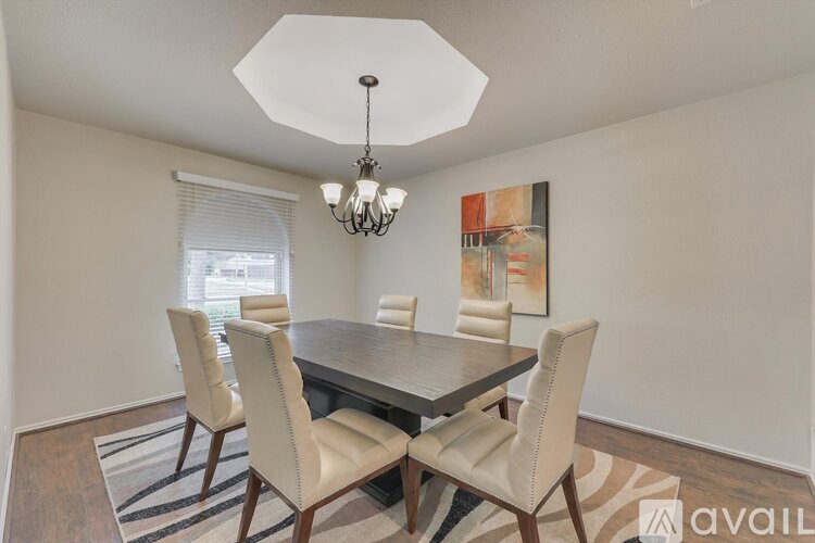 A dining room with a table and chairs and a chandelier.