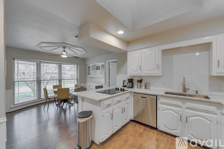 A kitchen with white cabinets and a wooden floor.