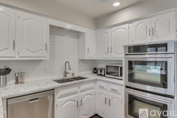 A kitchen with white cabinets and appliances.