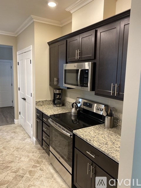 A kitchen with dark brown cabinets and granite countertops.