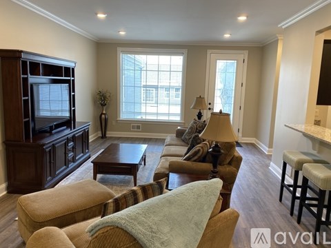 A living room with a brown wooden entertainment center and a striped chair.