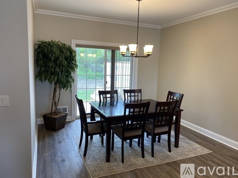 A dining room with a table and chairs and a potted plant.