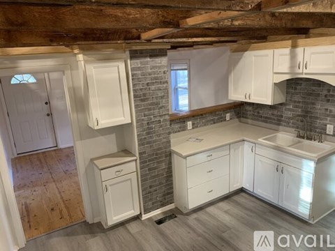 A kitchen with white cabinets and a brick wall.