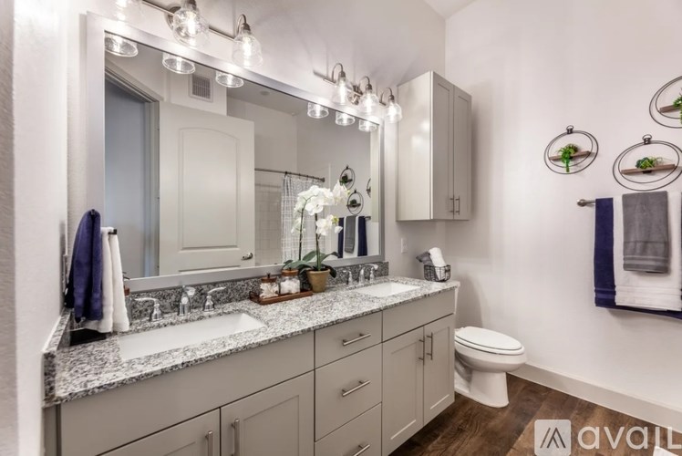 A bathroom with a large mirror, a sink, a toilet, and a cabinet.