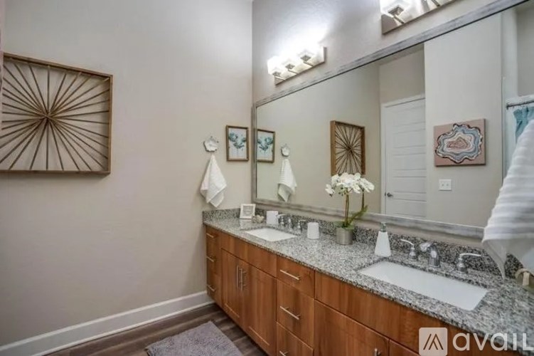 A bathroom with a large mirror, two sinks, and a wooden vanity.