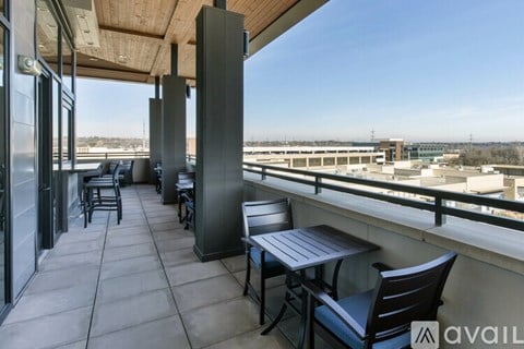 A balcony with a table and chairs overlooking a cityscape.