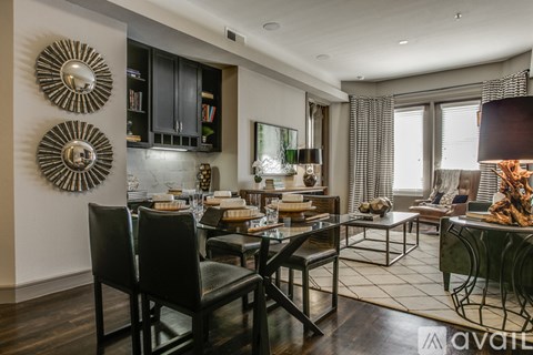 A modern dining room with a dark wood floor and a glass table.