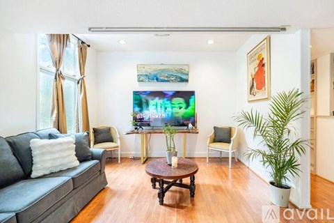 A living room with a grey couch, a wooden coffee table, and a painting on the wall.