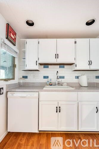 A kitchen with white cabinets and a wooden floor.