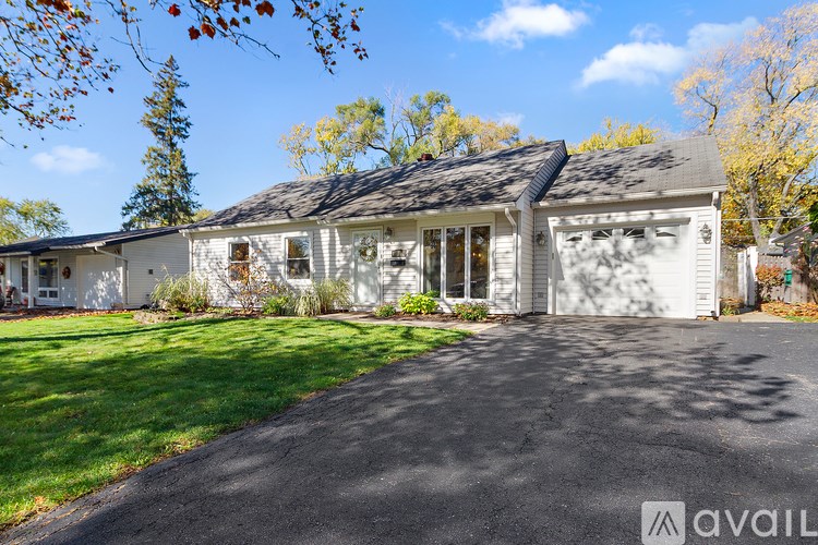 A white house with a black roof and a driveway in front.